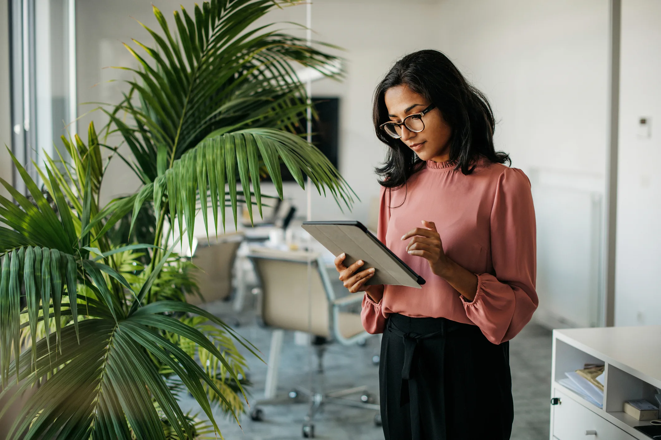 Professional woman using a tablet in an office, representing long term immigration planning and career decisions