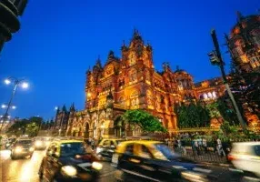 The Chhatrapati Shivaji Maharaj Terminus, a UNESCO World Heritage Site in Mumbai, glows at night with its stunning Victorian Gothic architecture, showcasing historic significance and bustling urban life.